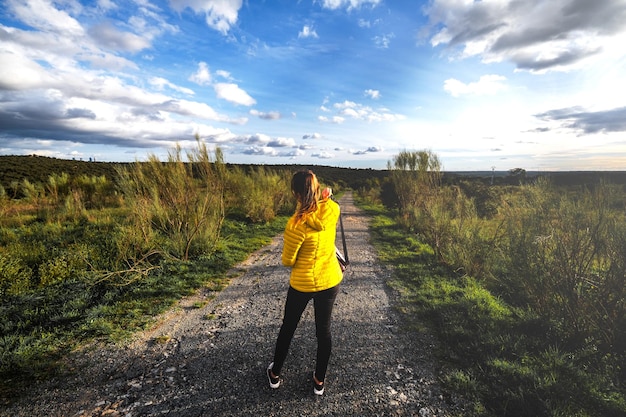 Foto mulher irreconhecível de casaco amarelo brilhante passeando pelo parque el pardo, em madrid