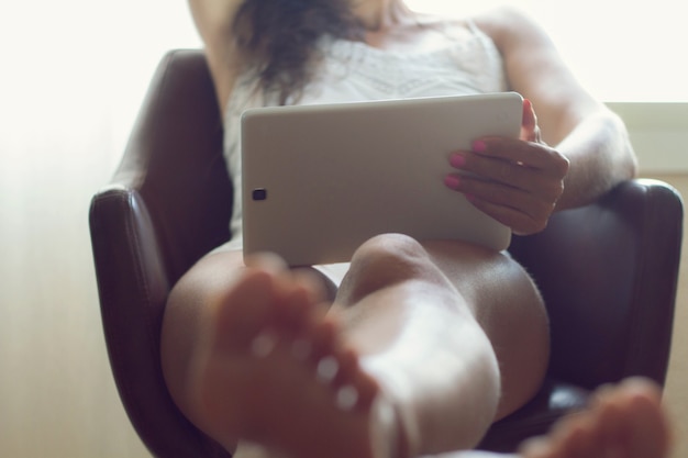 Mulher irreconhecível descansando lendo e se informando por meio de um dispositivo eletrônico