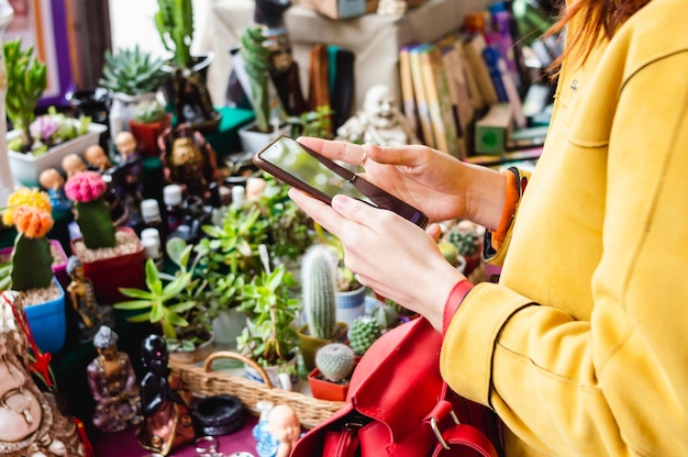 Mulher irreconhecível em uma feira de artesanato comprando mercadorias fazendo pagamentos do celular