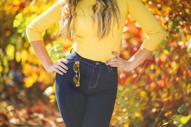 Mulher irreconhecível no outono. mulher vestindo jeans e suéter amarelo. menina ao ar livre. mulher elegante.