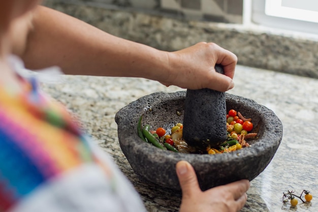 Mulher irreconhecível preparando um molho mexicano tradicional em um molcajete