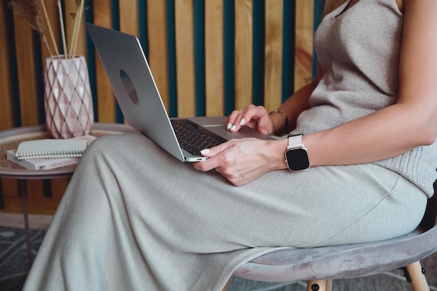 Mulher irreconhecível usando laptop fazendo conferência online sentada na cadeira no escritório em casa