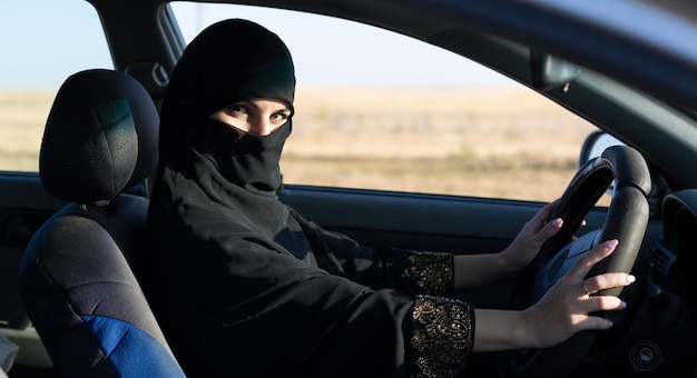 Mulher islâmica taxista dirigindo um carro.,