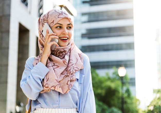 Mulher islâmica, usando telefone celular com sorrindo