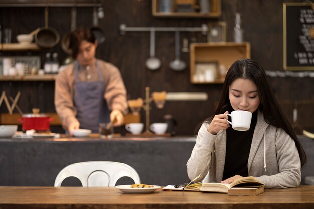 Mulher japonesa tomando café e lendo de um notebook em um restaurante