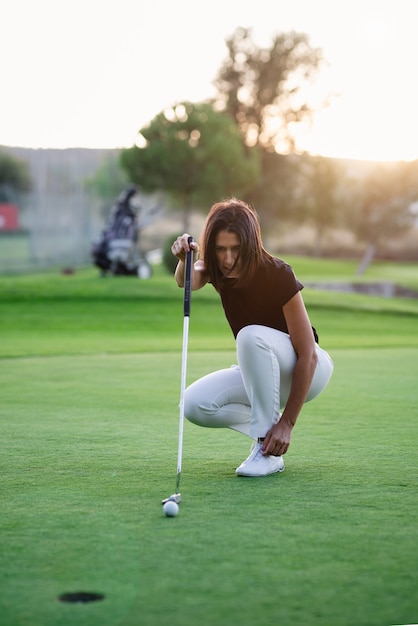 Mulher, jogador golf, verificar, linha, para, pôr, bola golfe mulher joga golfe, ligado, dia ensolarado, em, um, bonito, campo golfe