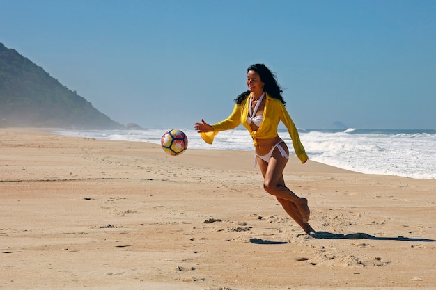 Mulher jogando bola na praia