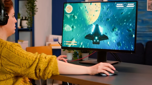 Mulher jogando esportes eletrônicos em casa usando um computador poderoso, participando do campeonato