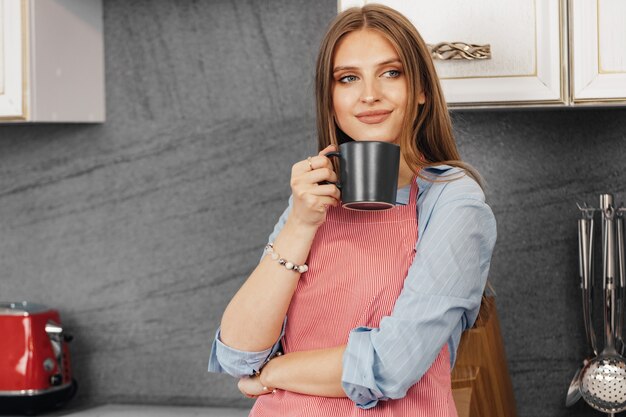 Mulher jovem a beber chá enquanto está na cozinha