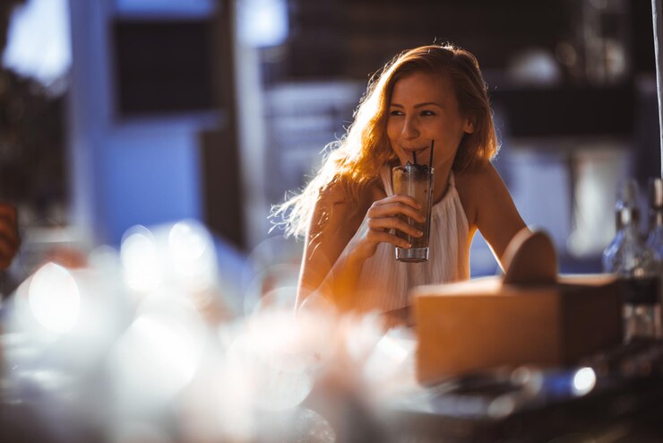 Foto mulher jovem a beber enquanto está sentada num café