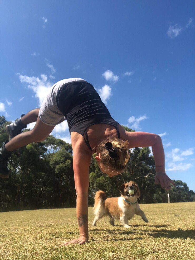Foto mulher jovem a brincar com o cão no campo contra o céu