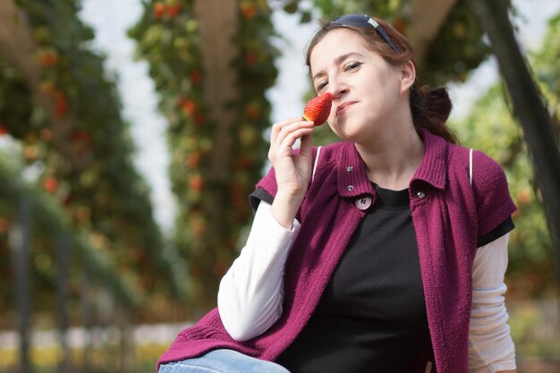 Foto mulher jovem a comer morango ao ar livre