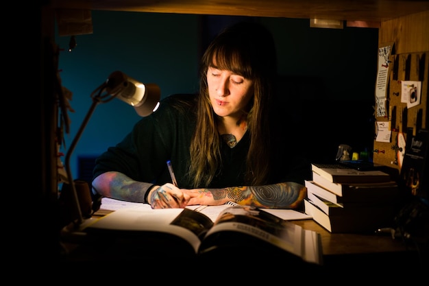 Foto mulher jovem a escrever num livro sentada em casa.