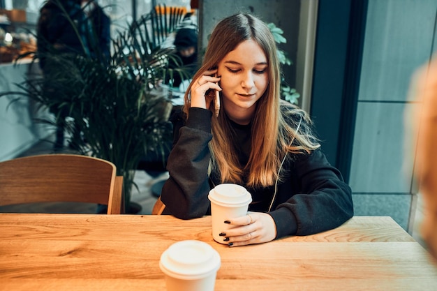 Foto mulher jovem a falar ao telefone num café a ter uma agradável chamada de telefone a atender chamadas a conversar