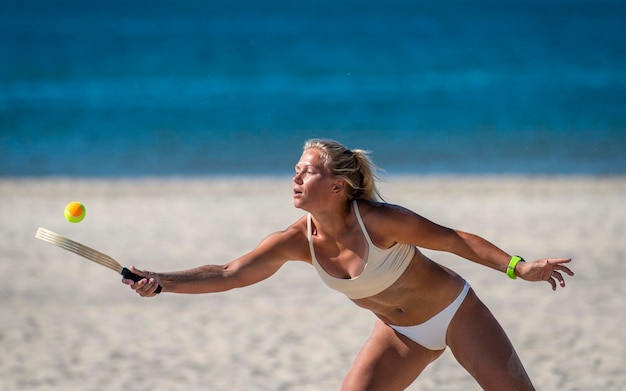 Mulher jovem a jogar ténis na praia