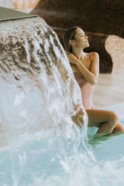 Foto mulher jovem a relaxar à beira da piscina coberta