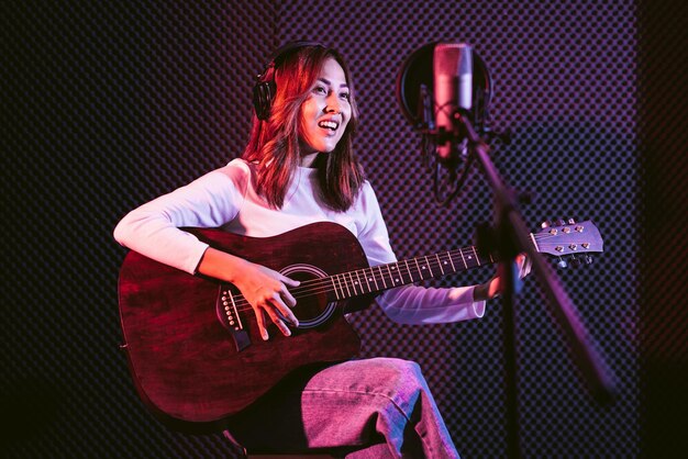 Foto mulher jovem a tocar guitarra.