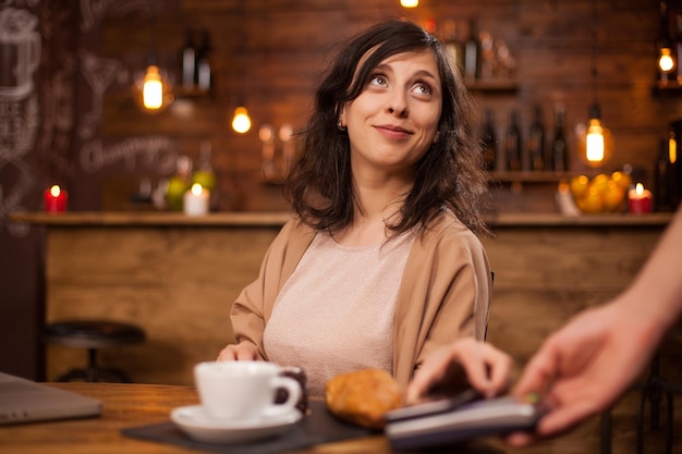 Mulher jovem a usar telemóvel à mesa
