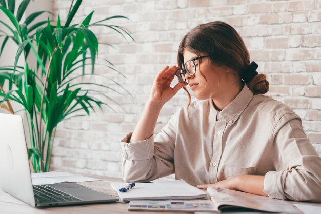 Mulher jovem a usar telemóvel à mesa