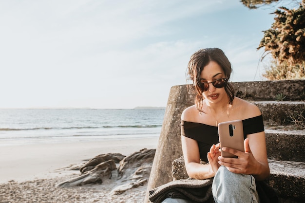 Foto mulher jovem a usar telemóvel na praia