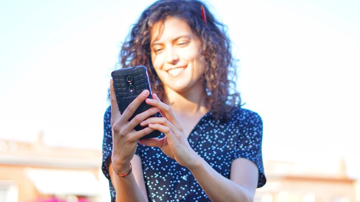 Foto mulher jovem a usar telemóvel.