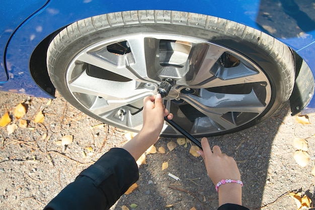 Mulher jovem a verificar o pneu do carro