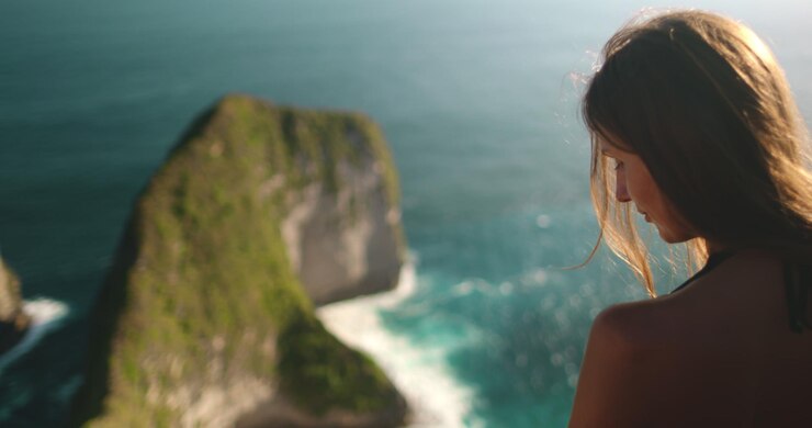 Foto mulher jovem admirando a vista deslumbrante do oceano do penhasco da ilha de nusa penida