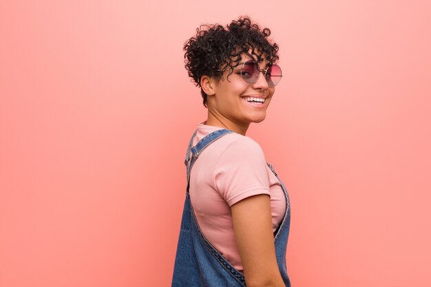 Mulher jovem adolescente americano africano misto olha de lado sorridente, alegre e agradável.