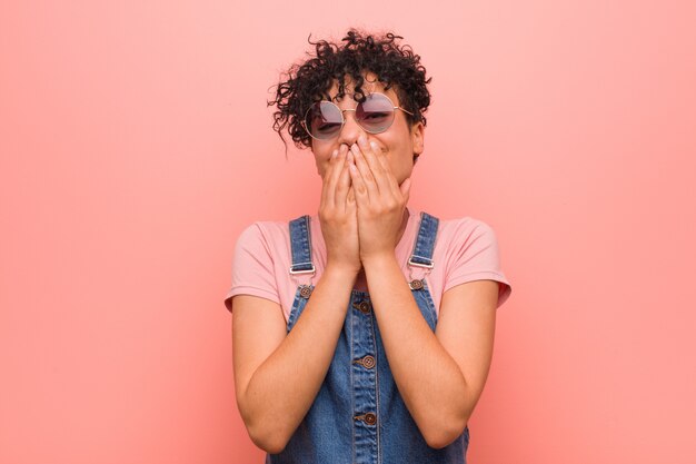 Mulher jovem adolescente americano africano misturado rindo de algo, cobrindo a boca com as mãos.