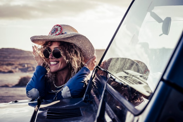 Mulher jovem adulta loira atraente na moda alegre sorria e aproveita a viagem de carro na aventura do campo - mulheres se divertem durante a viagem de veículo ao ar livre