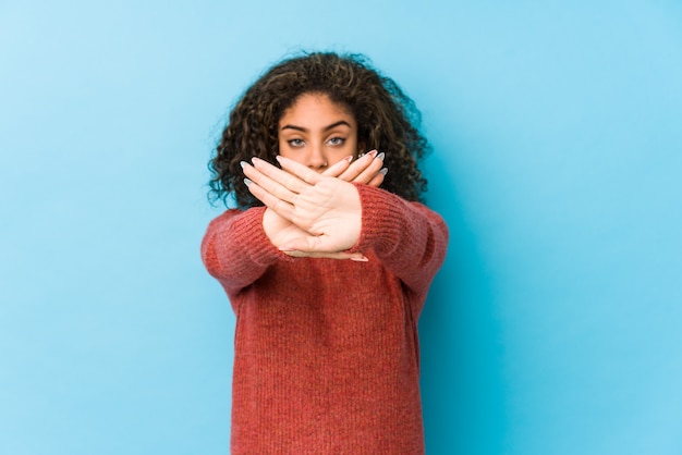 Mulher jovem afro-americana de cabelo encaracolado, fazendo um gesto de negação