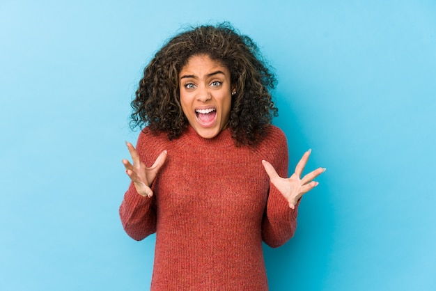 Mulher jovem afro-americana de cabelo encaracolado gritando de raiva.