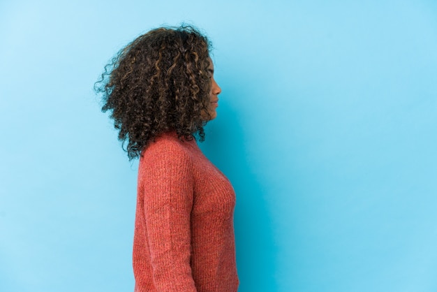 Mulher jovem afro-americana de cabelo encaracolado olhando para a esquerda, pose de lado.