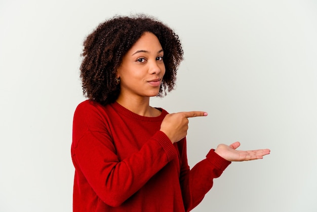 Mulher jovem afro-americana de raça mista isolada animado segurando um espaço de cópia na palma da mão.