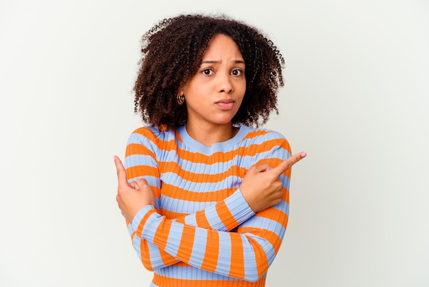 Mulher jovem afro-americana de raça mista isolada aponta lateralmente, está tentando escolher entre duas opções.