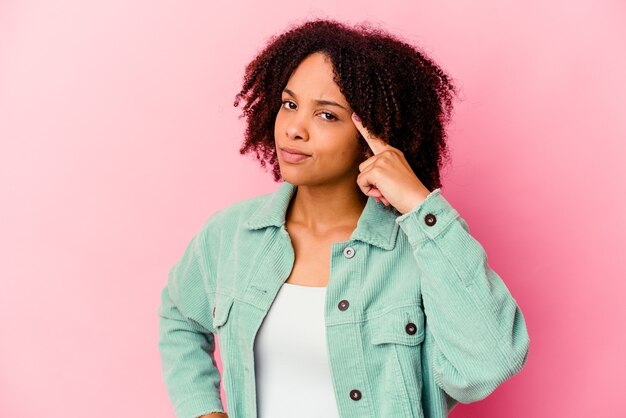 Mulher jovem afro-americana de raça mista isolada apontando o templo com o dedo, pensando, focado em uma tarefa.