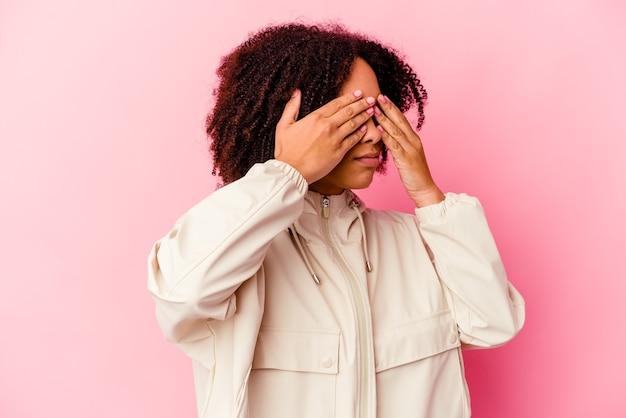 Mulher jovem afro-americana de raça mista isolada com medo, cobrindo os olhos com as mãos.