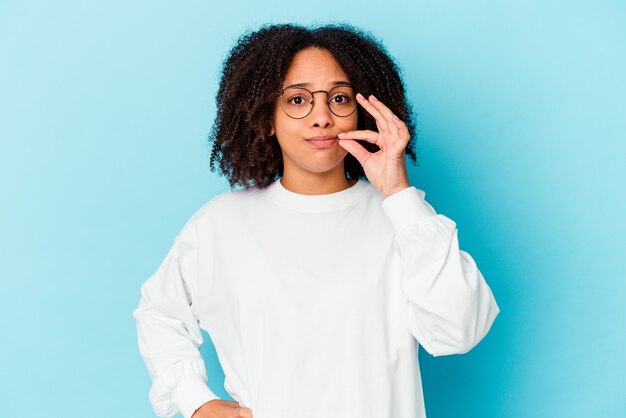 Mulher jovem afro-americana de raça mista isolada com medo, cobrindo os olhos com as mãos.