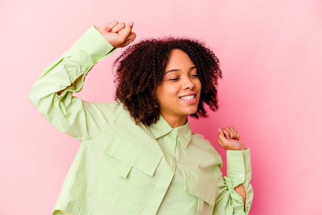 Mulher jovem afro-americana de raça mista isolada comemorando um dia especial, pula e levanta os braços com energia.