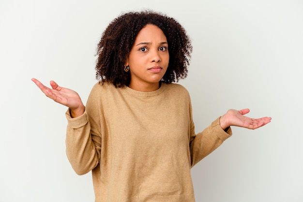 Mulher jovem afro-americana de raça mista isolada duvidando e encolhendo os ombros num gesto de questionamento.