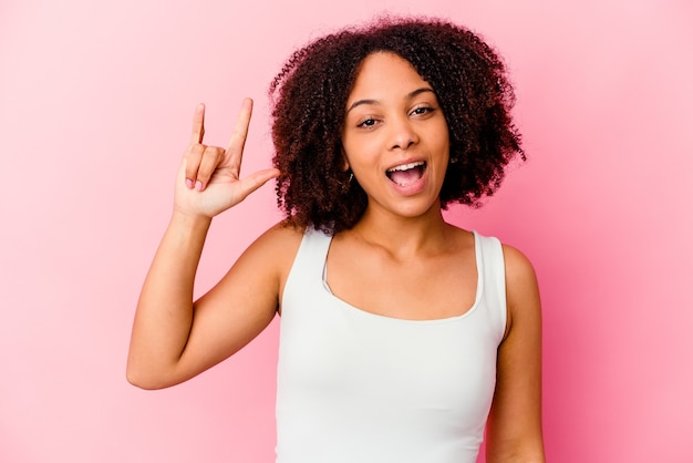 Mulher jovem afro-americana de raça mista isolada mostrando um gesto de chifres como um conceito de revolução.