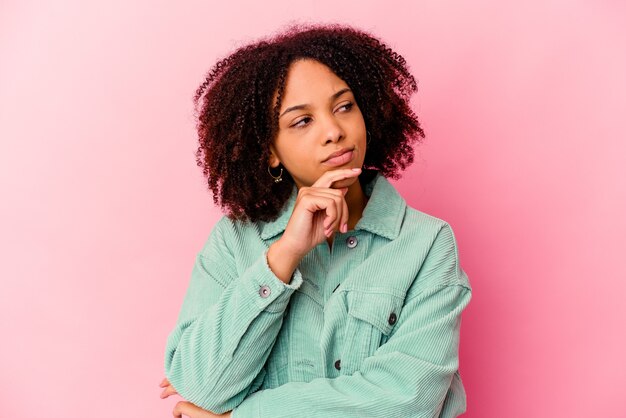 Mulher jovem afro-americana de raça mista isolada olhando de soslaio com expressão duvidosa e cética.