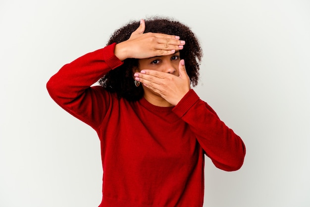 Mulher jovem afro-americana de raça mista isolada piscar para a câmera por entre os dedos, rosto cobrindo vergonha.