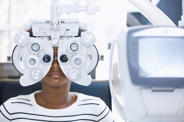 Mulher jovem afro-americana exame ocular com oftalmologia de diagnóstico em clínica óptica