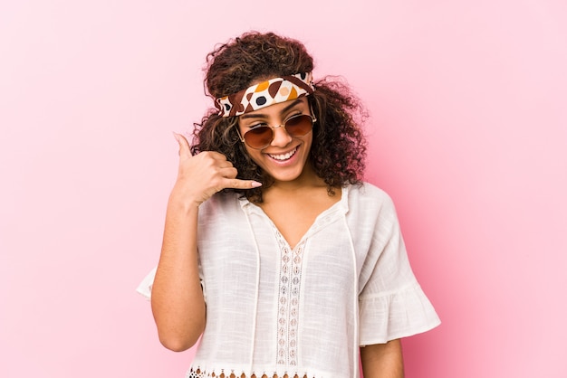 Mulher jovem afro-americana hipster isolada na parede rosa, mostrando um gesto de chamada de telefone móvel com os dedos.