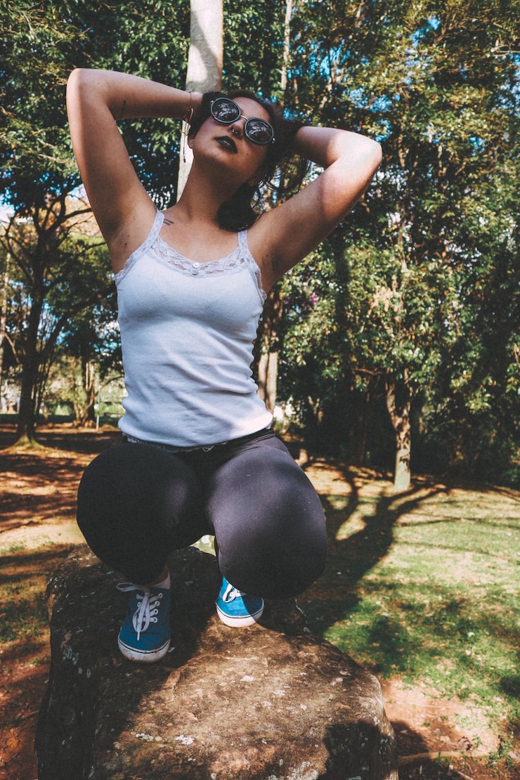 Foto mulher jovem agachada em uma rocha no parque