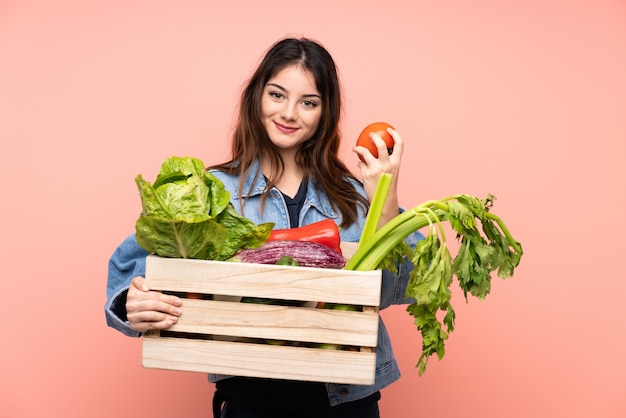 Mulher jovem agricultor segurando uma cesta cheia de legumes frescos