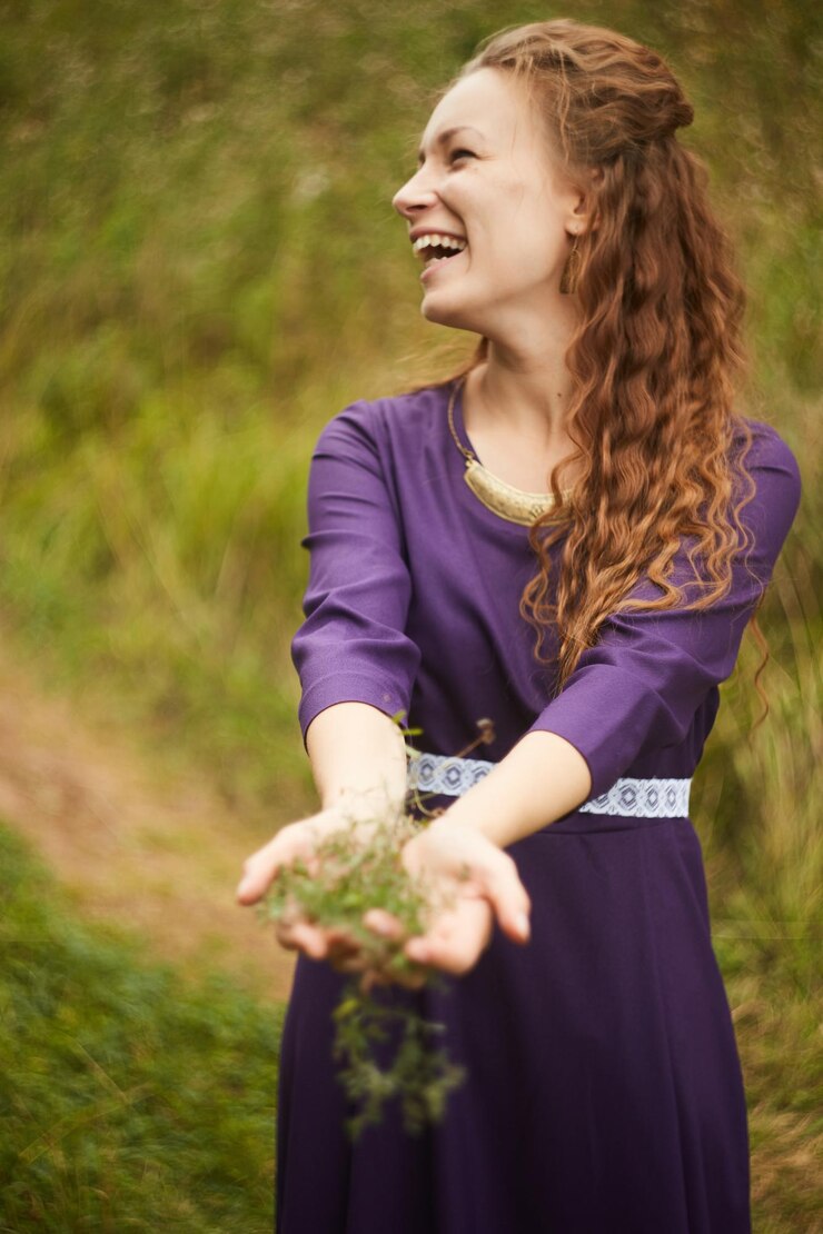 Foto mulher jovem alegre segurando plantas enquanto está de pé no campo