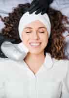 Foto mulher jovem alegre tendo procedimento de levantamento de rosto na clínica