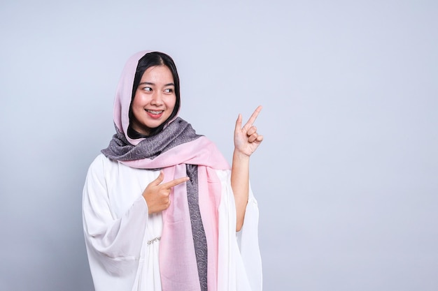 Mulher jovem alegre usando véu apontando para o lado Conceito de venda promocional do Eid